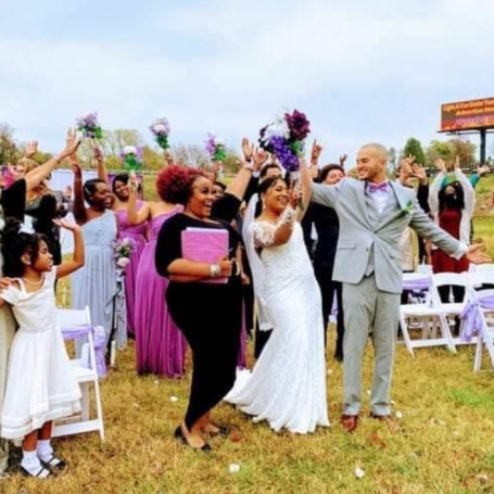 A joyful wedding celebration with guests holding flowers and cheering outdoors. Seasoned Celebrant.